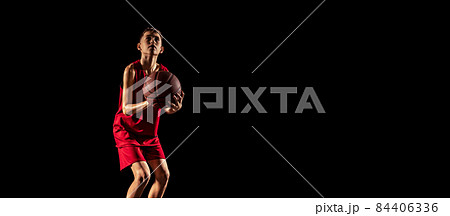 Portrait of young boy, basketball player in motion, training isolated over black background 84406336