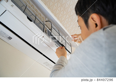 エアコンのフィルターを取り出す男性の様子 エアコンのフィルターを取り出す男性の様子 84407296