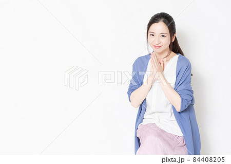 白い壁の前の椅子に座ってお願いのポーズをする主婦 白い壁の前の椅子に座ってお願いのポーズをする主婦 84408205