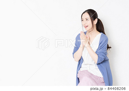 白い壁の前の椅子に座ってお願いのポーズをする主婦 白い壁の前の椅子に座ってお願いのポーズをする主婦 84408206
