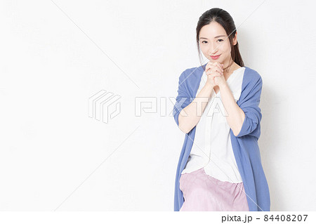 白い壁の前の椅子に座ってお願いのポーズをする主婦 84408207