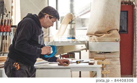Man using a hand saw to cut wood 84408306