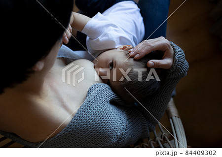 young woman breastfeeding her little son while sitting in a cozy armchair young woman breastfeeding her little son while sitting in a cozy armchair 84409302