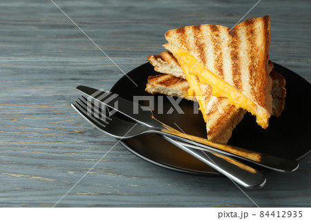Plate with grilled sandwiches and cutlery on wooden table Plate with grilled sandwiches and cutlery on wooden table 84412935