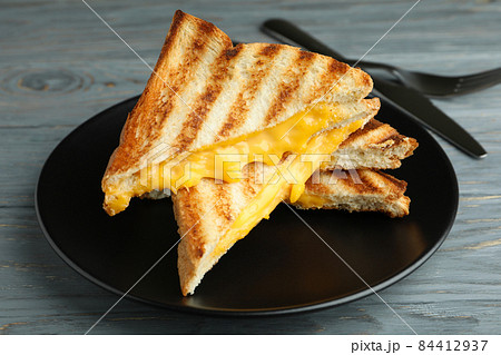 Plate with grilled sandwiches and cutlery on wooden table 84412937