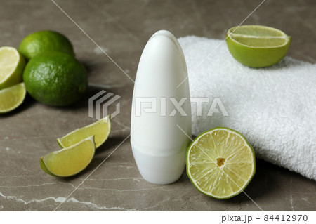 Blank deodorant, limes and towel on gray table 84412970