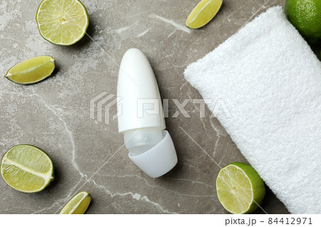 Blank deodorant, limes and towel on gray table 84412971