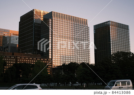 夕暮れに照らされたオフィスビル群、夕焼けの街並み、夕焼けに照らされた高層ビル 84413086