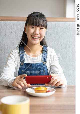 ファミリーレストランでデザートをスマホで写真に撮る中学生の女の子 84415535