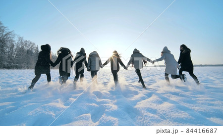 Cheerful girls run across the snow-covered field. Cheerful girls run across the snow-covered field. 84416687