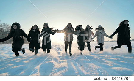 Cheerful girls run across the snow-covered field. 84416706