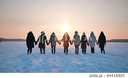 A group of girls stand holding hands on the field in winter. A group of girls stand holding hands on the field in winter. 84416805
