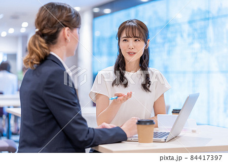 カフェで英会話の勉強をする日本人の若い女性と西洋人の先生 84417397