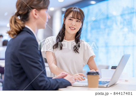 カフェで英会話の勉強をする日本人の若い女性と西洋人の先生 84417401