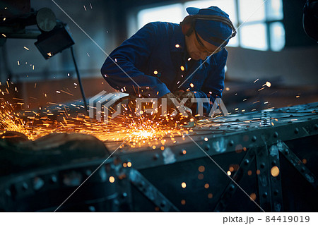 Worker polishing new modern fence with sparks.  84419019