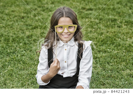 Last day of school. Happy girl hold prop glasses green grass. 84421243