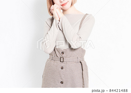 白背景の前に立ってお願いのポーズをする若い女の子 84421488