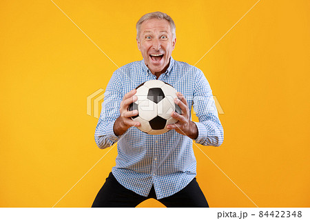 Mature man posing with soccer ball on yellow background 84422348