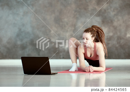 Woman takes online yoga asana lessons using laptop. Woman takes online yoga asana lessons using laptop. 84424565