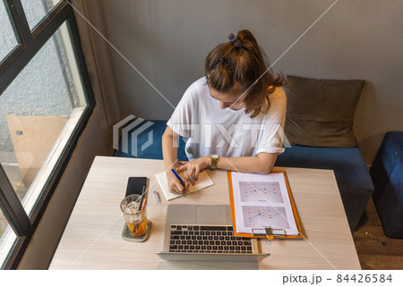 Asian woman writing notes and financial chart report Asian woman writing notes and financial chart report 84426584