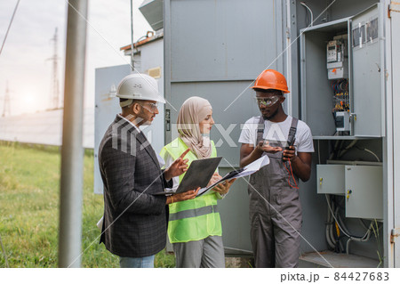 Multiracial people examining solar panels on station Multiracial people examining solar panels on station 84427683