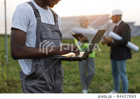 Close up of technician working on laptop at solar farm 84427693