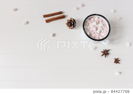 Christmas styled composition. Hot chocolate, marshmallow,cinnamon sticks, anise stars. Pine cones on white wooden table background. Festive winter breakfast concept. Flat lay, top view, copy space. 84427706