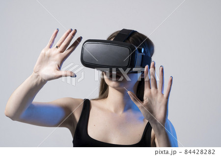 Modern architect, designer woman wearing VR goggles and interacts with metaverse using swipe and stretching gestures. Future technology concept. 84428282