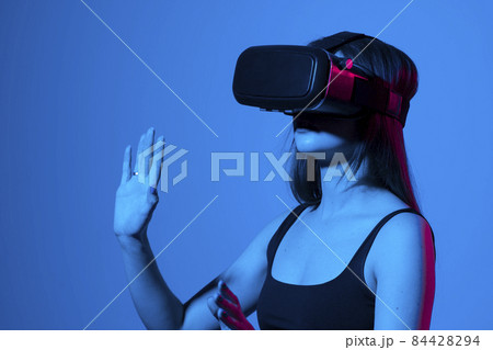 Young woman using VR headset helmet to play simulation game. Watching virtual reality 3d video. Girl in VR goggles looking around. Young woman using VR headset helmet to play simulation game. Watching virtual reality 3d video. Girl in VR goggles looking around. 84428294