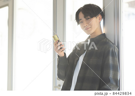 スマホを持つ爽やかな若い男性 84429834