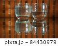 2 glasses with water and reflections on an orange checkered background 84430979