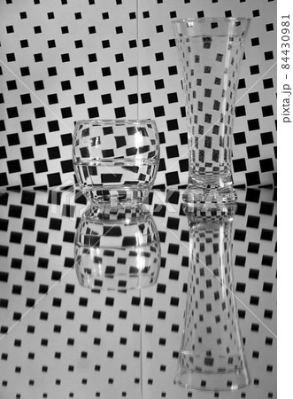 glasses with water and reflections on black and white checkered background glasses with water and reflections on black and white checkered background 84430981
