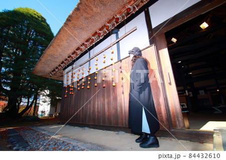 旅先で民家の軒先にある干し柿の横にいる女性 旅先で民家の軒先にある干し柿の横にいる女性 84432610