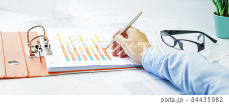 Finance. Female hand with calculator on financial graphs on desk 84435982