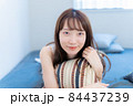 ベッドで寝転びながら微笑む女性 84437239