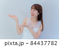 両手で紹介するポーズを取る女性 84437782