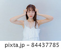 両手を頭に当て困るポーズをする女性 84437785