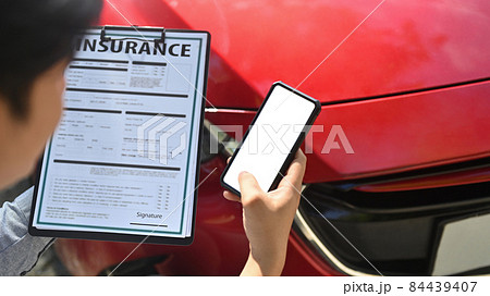 Insurance agent using smart phone while examining car after accident. 84439407