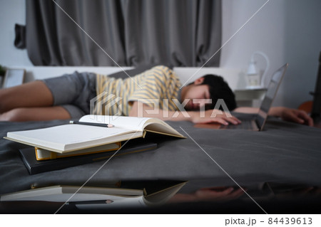 Tired asian man sleep on the bed with books at night. 84439613