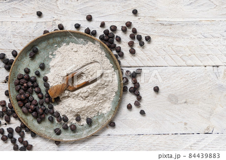 Plate and wooden scoop of black chickpea flour and beans top view 84439883