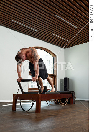 Pilates reformer workout exercises man at gym indoor. 84442773