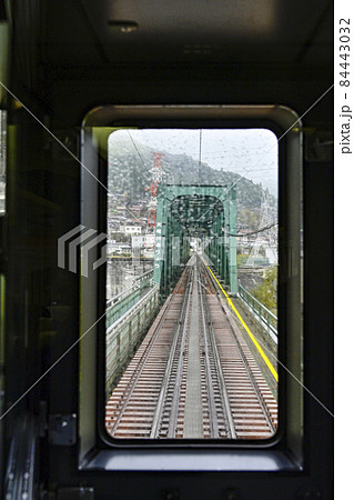 雨の中走行する飯田線秘境駅号車窓より天竜川橋梁を望む 84443032