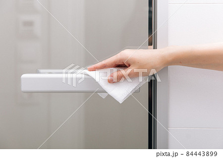 Cleaning glass door handles with an antiseptic wet wipe. Sanitize surfaces prevention in hospital and public spaces against corona virus. Woman hand using towel for cleaning home room door link. Cleaning glass door handles with an antiseptic wet wipe. Sanitize surfaces prevention in hospital and public spaces against corona virus. Woman hand using towel for cleaning home room door link. 84443899