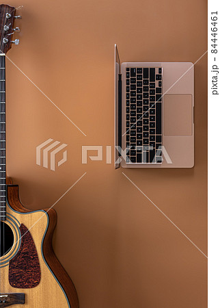 Acoustic guitar and laptop on a brown background, top view, copy space. 84446461