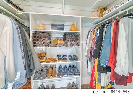 Organized unisex small walk in closet interior with shoe rack in the middle 84446943