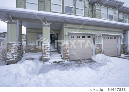 Exterior of a house with two garage doors and stone bricks siding 84447838