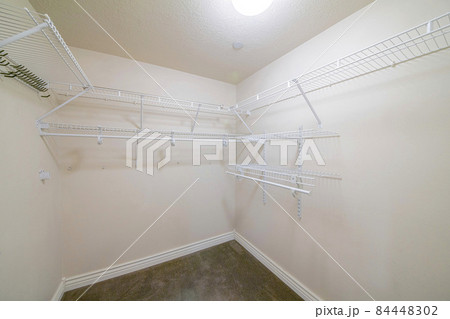 Interior of a windowless walk in closet with brown carpet flooring Interior of a windowless walk in closet with brown carpet flooring 84448302