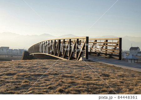 Curved bridge with metal beams and wooden railings with banister Curved bridge with metal beams and wooden railings with banister 84448361