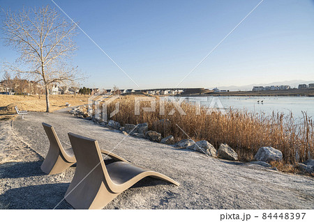 Two lounge chairs along the trail at the side of the lake waterfront 84448397