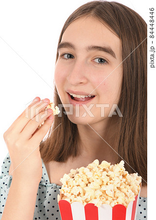 Teenage girl eating popcorn, standing on white. Teenage girl eating popcorn, standing on white. 84448446